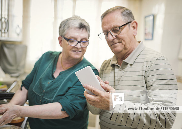 Senior couple looking at smartphone at home