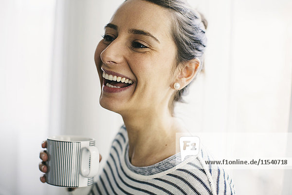 Lachende Frau mit einer Tasse Kaffee