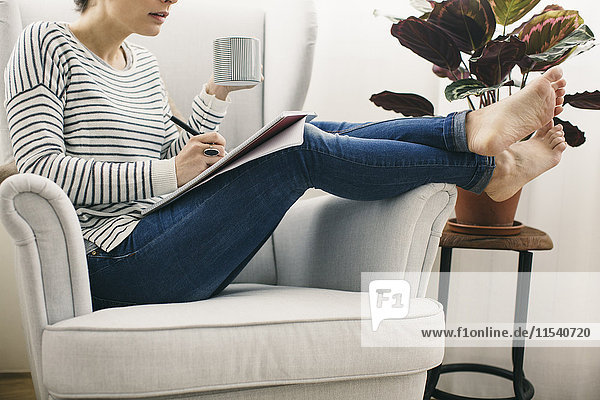 Frau im Sessel sitzend schreibt auf Notizblock