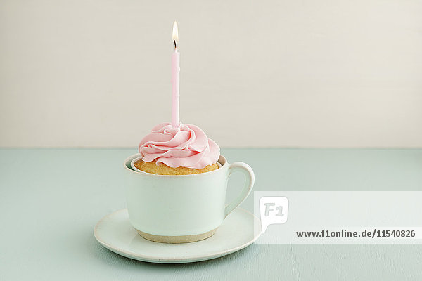 Tasse Kuchen mit angezündeter Kerze in einer Tasse