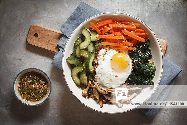 Vegetarische koreanische Reisschüssel mit Champignon  Spinat  Gurke  Karotte und Spiegelei
