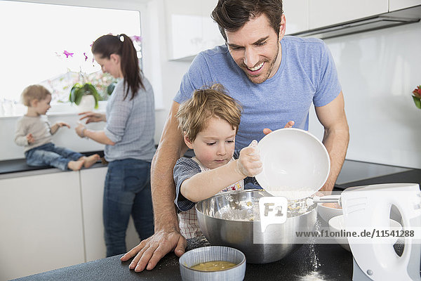 Familie mit zwei Kindern beim Kochen in der Küche