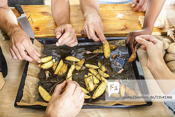 Friends eating potato wedges from baking tray