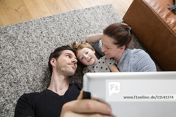 Glückliche Familie auf dem Boden liegend  mit digitalem Tablett