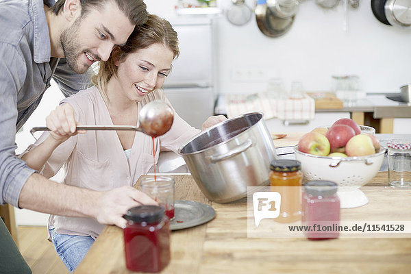Paar in der Küche füllen Marmelade in Gläsern