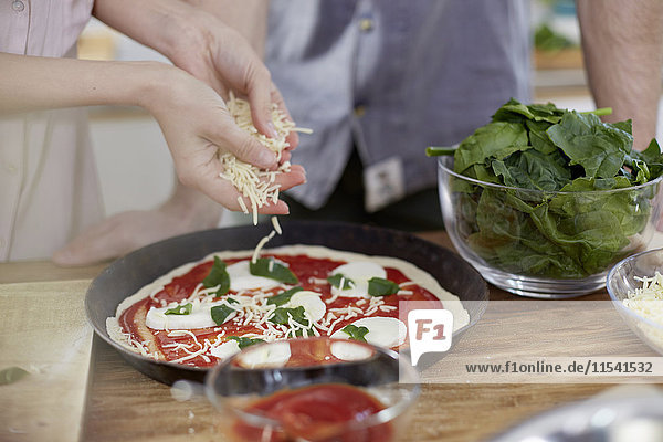 Couple preparing pizza in kitchen