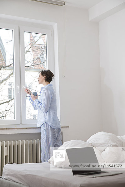 Woman in bedroom looking out of window