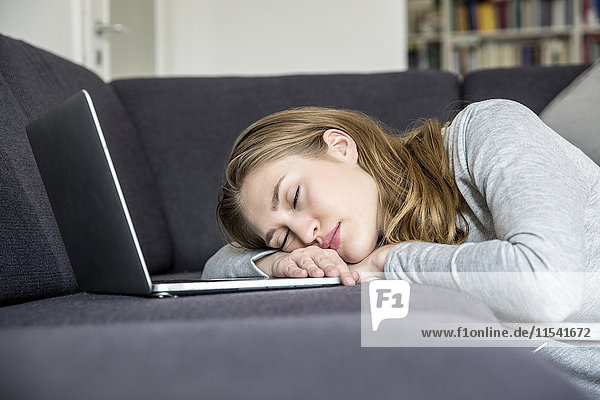 Young woman with laptop relaxing on her couch at home