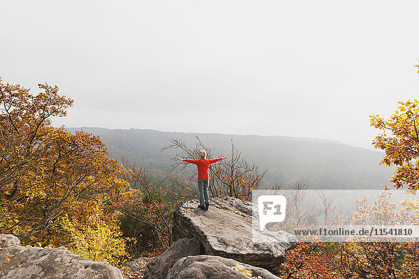 Deutschland  Rheinland-Pfalz  Pfälzer Wald  Frau beim Yoga auf dem Drachenfels im Herbst