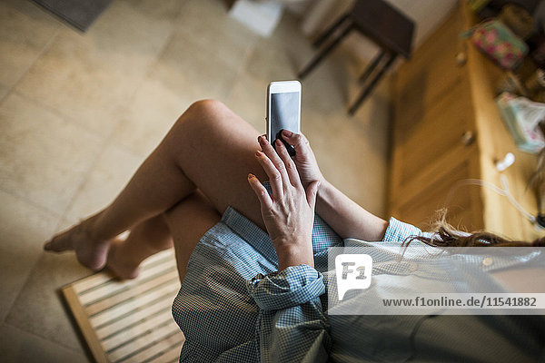 Junge Frau im Bad mit Smartphone