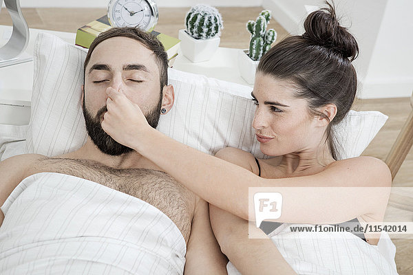 Paar im Bett liegend mit Mann schnarchend