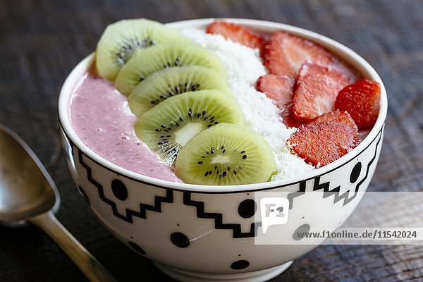 Schale Erdbeer-Smoothie mit Kiwi  Erdbeeren und Kokosraspeln in Scheiben geschnitten