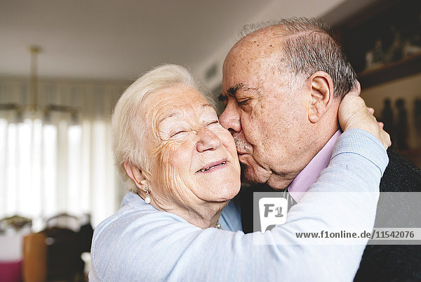 Seniorenpaar  das sich zu Hause umarmt und küsst.