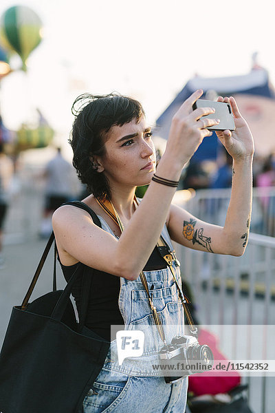 USA  New York  Coney Island  junge Frau  die im Vergnügungspark einen Selfie macht