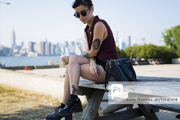 USA  New York City  Brooklyn  tätowierte junge Frau auf einer Bank sitzend
