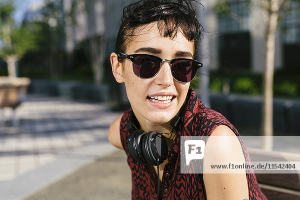 Portrait of young woman with headphones wearing sunglasses