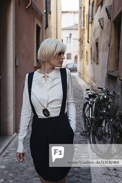 Italien  Verona  modische blonde Frau in einer engen Gasse stehend