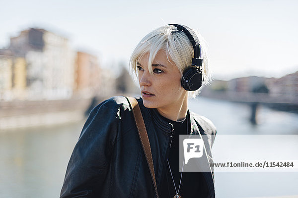 Italien  Verona  Portrait einer blonden Frau beim Musikhören mit Kopfhörern
