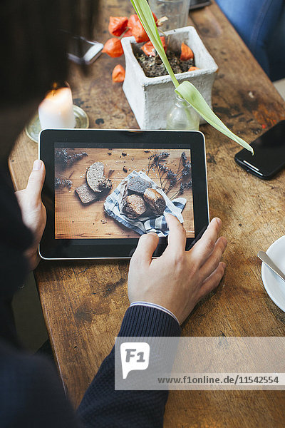 Mann im Café mit Bild auf digitalem Tablett