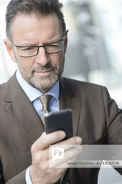 Porträt eines Geschäftsmannes mit Brille auf seinem Smartphone
