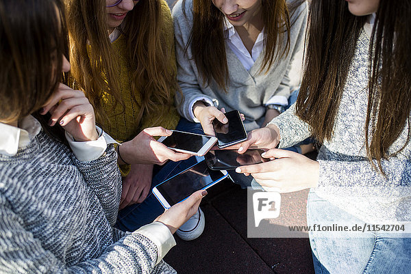 Four young women comparing her smartphones