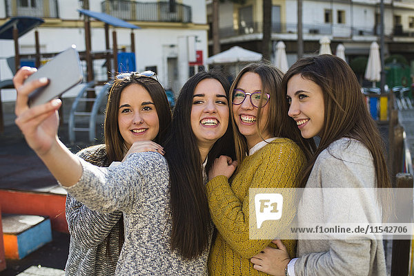 Vier junge Frauen nehmen einen Selfie mit Smartphone