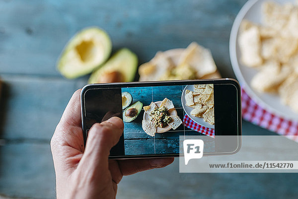 Taking a picture of nachos and guacamole with smartphone  close-up