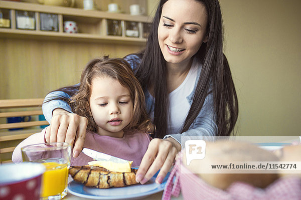 Porträt der Mutter und ihrer kleinen Tochter zusammen am Frühstückstisch