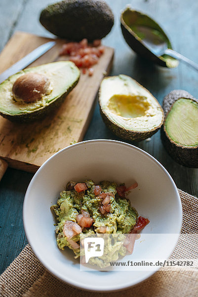 Geschnittene und ganze Avocado und Schale mit Guacamole