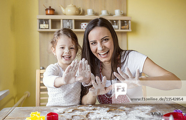 Portrait of laughing mother and her little daughter baking together