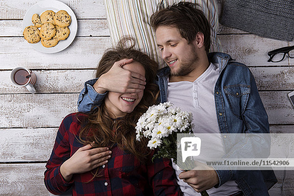 Junger Mann überrascht seine Freundin mit Blumen
