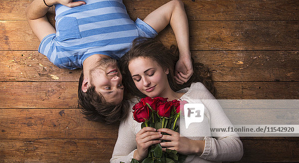 Verliebtes junges Paar auf Holzboden liegend