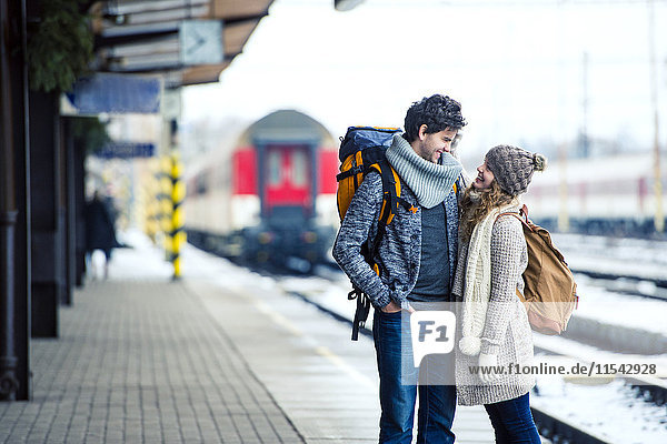 Lächelndes junges Paar auf dem Bahnsteig