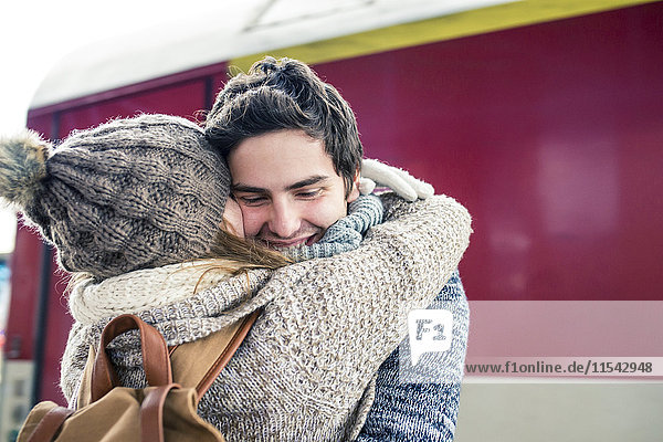 Happy young couple embracing in front of train