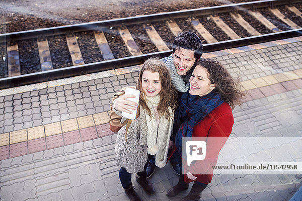 Drei Freunde auf dem Bahnsteig mit einem Selfie.