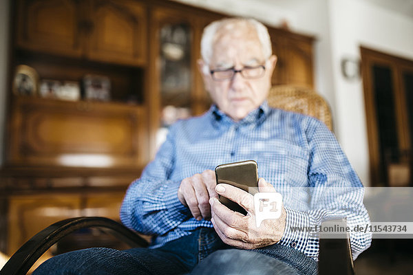 Senior Mann mit Smartphone zu Hause  Nahaufnahme