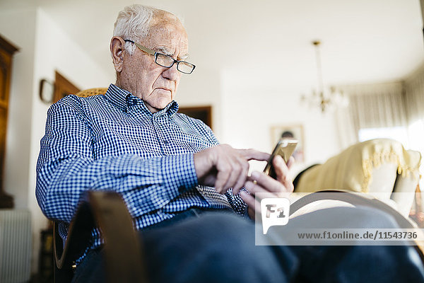 Senior Mann mit Smartphone zu Hause