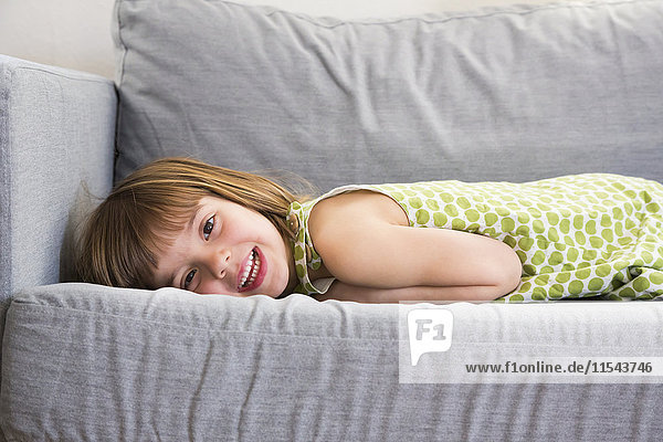Porträt des lächelnden Mädchens auf der Couch liegend