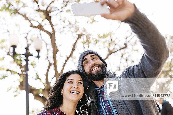 Junges glückliches Paar mit einem Selfie im Freien