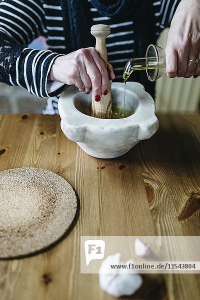 Frau bereitet Knoblauchmayonnaise in ihrer Küche zu