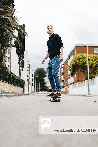 Spanien  Torredembarra  lächelnder junger Mann auf seinem Skateboard