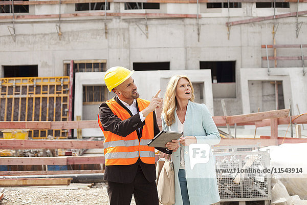 Mann mit Schutzhelm im Gespräch mit Frau auf der Baustelle