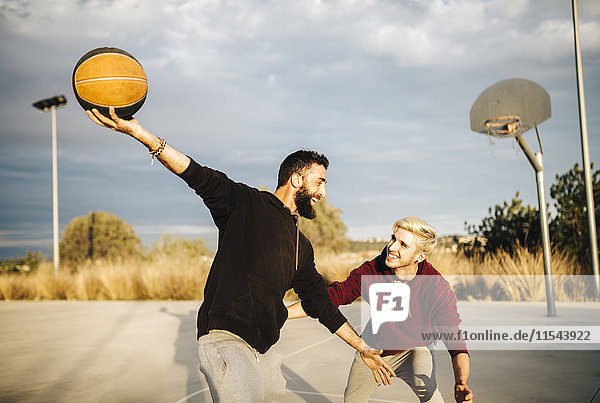 Zwei junge Männer beim Basketballspielen auf einem Außenplatz