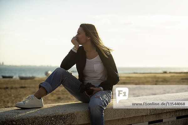 Spanien  Puerto Real  Frau entspannt an der Wand vor dem Strand