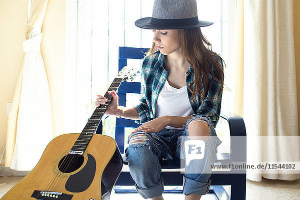 Young woman with guitar indoors
