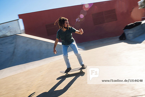 Junger Mann mit Dreadlocks Skateboarden im Skatepark