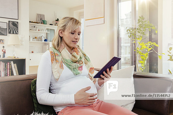Pregnant woman using digital tablet at home