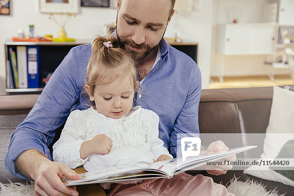 Father and little girl reading a book at home