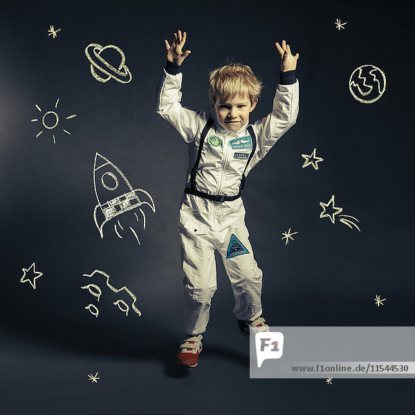 Kind mit Raumanzug umkreist von Himmelskörpern und Koryphäen