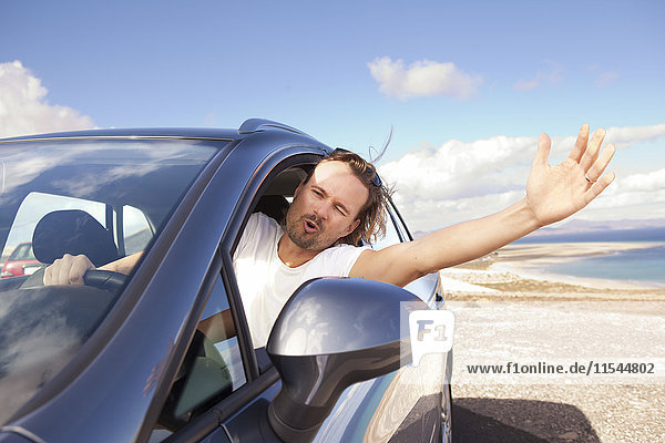 Spanien  Fuerteventura  Jandia  glücklicher Mann im Auto an der Küste